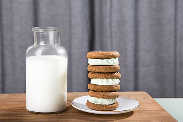 Milk jugs and cookies on gray background
