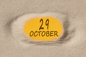 October 29. 29th day of the month, calendar date. Hole in sand. Yellow background is visible through hole. Autumn month, day of the year concept