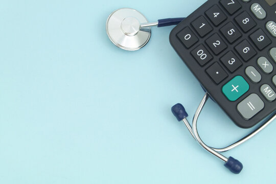 Stethoscope and calculator on blue background with copy space. Cost of medicine concept.	