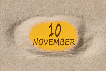 November 10. 10th day of the month, calendar date. Hole in sand. Yellow background is visible through hole. Autumn month, day of the year concept