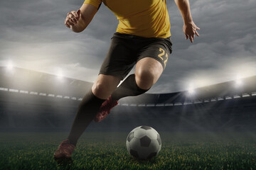 Cropped male soccer, football player dribbling ball at the stadium during sport match on dark sky background.