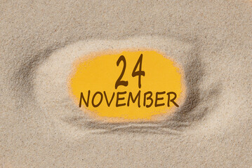 November 24. 24th day of the month, calendar date. Hole in sand. Yellow background is visible through hole. Autumn month, day of the year concept