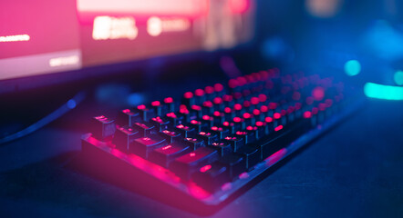 Closeup keyboard professional cyber gamer studio room with neon color blur banner background, soft focus