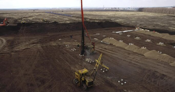 Equipment for installing piles in ground, heavy machines for driving pillars work in laying the foundation building. Construction aerial view height.