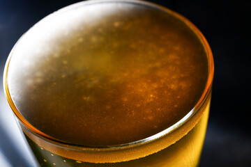 Glass of cold drink in yellow on black background