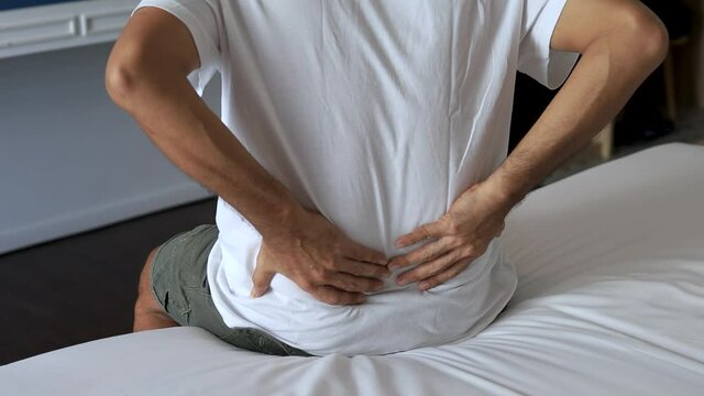 young man suffering from back pain on the bed, healthcare and problem concept