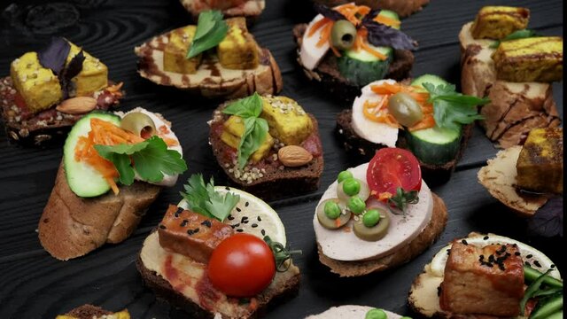 Delicious snacks. Bruschetta snacks. Variety of small sandwiches with vegetables - tomato, arugula, pepper. view from above. top view. black wood background