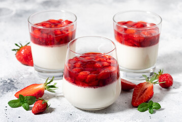 Creamy vegan panna cotta with coconut and strawberries in glasses on gray background. Traditional Italian dessert. close-up