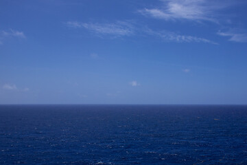 An ocean scene. The aquatic seascape is shot from an elevated position out into the wide open sea and sky