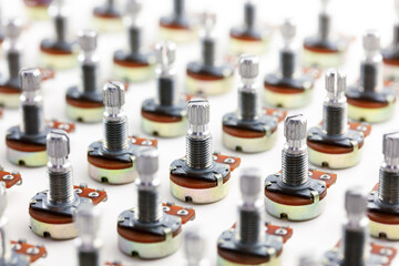 Electronic parts aligned. Many potention meters or variable resistors (also called volume pots) aligned on neutral white background.