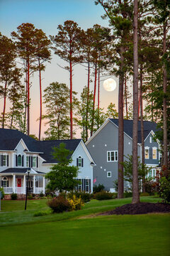 Full moon at sunset over beautiful suburban houses