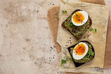Healthy sandwich with avocado, eggs and microgreens on toast on a serving plate for breakfast. Healthy nutrition dietary concept. Top view