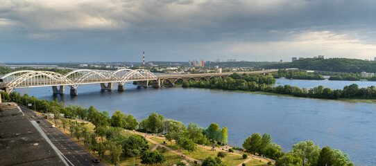 Obraz premium Panoramic view of the right bank of Kyiv. Dnieper river, evening and sunset. Metro bridge. Sight. Nice view from the balcony.