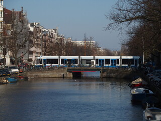 Eine Straßenbahn fährt über eine Grachtenbrücke in Amsterdam, Niederlande