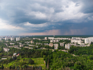 Fototapeta na wymiar Aerial view on green Kharkiv city center Botanical garden and Pavlove Pole. Multistory buildings with telecommunication tower antenna with scenic rainy dark heavy clouds sky