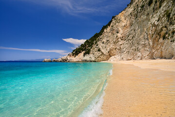 Fototapeta na wymiar Sandy beach with rocky mountains and clear blue sea along the northern coast of the Greek island of Ithaca in the Ionian Sea
