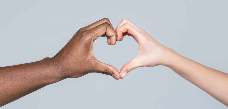 Charity, love and diversity - closeup of female and male hands of different skin color making heart shape. People different skin colors put their hands together making heart shape in white background