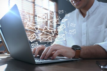 Businessman sending emails at table indoors, closeup