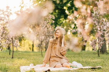 cute young woman, with long blond hair, enjoys the blooming of the spring apple tree garden, woman...