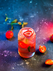 Summer refreshing strawberry mojito, colored neon lighting on a dark table.