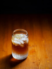 Cold espresso coffee tonic in a glass with ice on a wooden table