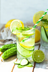 Refreshing cold summer drink: cucumber lemonade with lemon, lime and mint in a glass. Detox, light beverage with natural organic ingredients for hot weather. Close up macro copy space