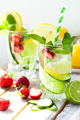 Refreshing cold summer drink: cucumber lemonade with strawberry, lemon, lime, mint in a glass. Detox, light beverage with natural organic ingredients for hot weather. Close up macro copy space