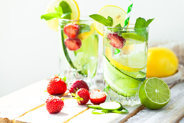 Refreshing cold summer drink: cucumber lemonade with strawberry, lemon, lime, mint in a glass. Detox, light beverage with natural organic ingredients for hot weather. Close up macro copy space