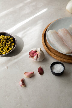 Garlic and salt near fish and peas