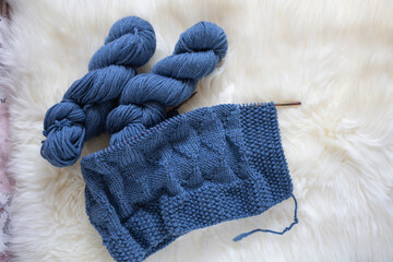 Hand Knitted blue merino baby blanket in basket on white background