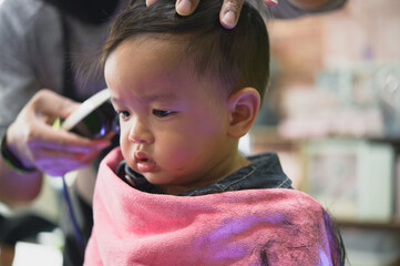 Asian Toddler child getting his first haircut.