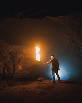 Man with burning fire in dark cave