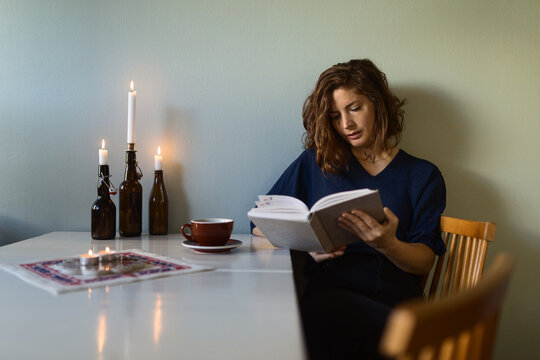 Woman reading book near candles
