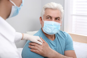 Doctor taking care of senior man with protective mask at nursing home