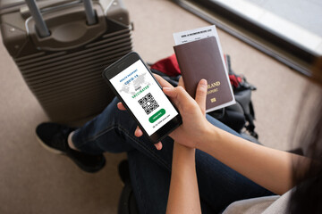 Smartphone on hand of woman traveler with health passport of vaccination certification in the...