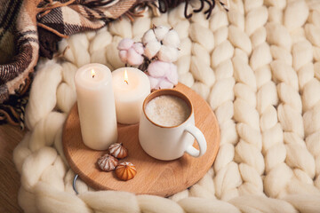 Cup of cappuccino and cookies, candles, checkered plaid, inscription Home on the background of blanket of thick yarn.