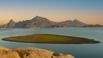A View during an early morning glow of a small green island in the middle of Jawai dam at Rajasthan...