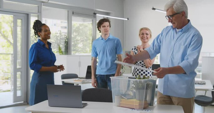 Retired man packing stuff in plastic box at workplace in office