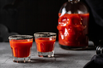 Tomato cocktail in a skull-shaped bottle and glasses. Drink for Halloween party