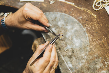 Joyero trabajando en su taller colocando una gema en un anilo de oro