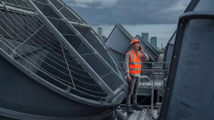 Senior Mechanical engineer call phone on cooling tower on background.