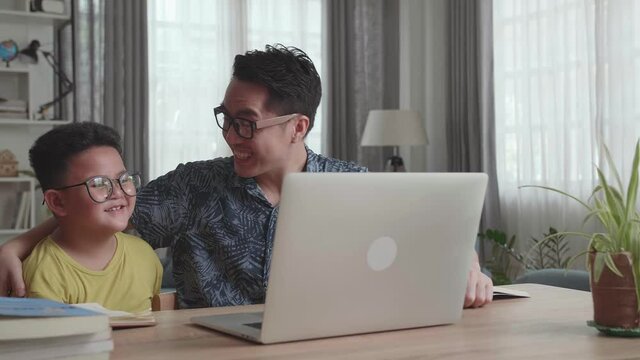 Happy Asian Father And His Son Having Video Call In Living Room

