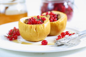 Baked apples with honey, walnuts, currants on a white background