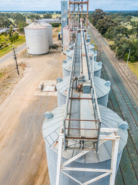 Looking along the tops of a line of grain silos between a road and a railway line