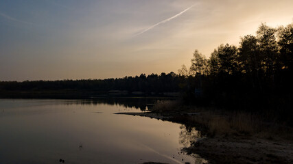Fototapeta premium Aerial view of a beautiful and dramatic sunset over a forest lake reflected in the water, landscape drone shot. Blakheide, Beerse, Belgium. High quality photo