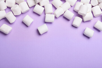 Fototapeta na wymiar Delicious puffy marshmallows on lilac background, flat lay. Space for text