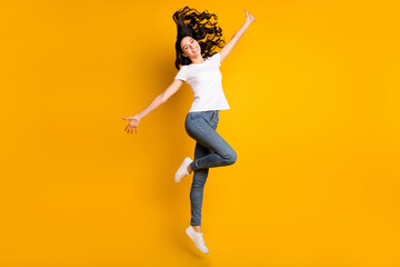 Fototapeta na wymiar Photo of pretty charming young lady dressed white t-shirt jumping high hands arms sides isolated yellow color background