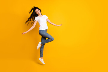 Fototapeta na wymiar Full length body size view of lovely cheerful girl jumping having fun dancing isolated over bright yellow color background