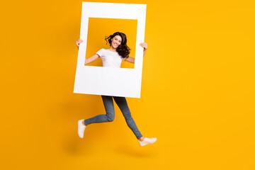 Full size photo of happy woman jump up air hold frame portrait isolated on funky yellow color...