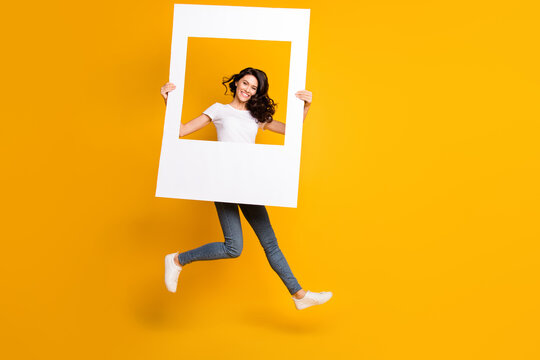 Full size photo of happy woman jump up air hold frame portrait isolated on funky yellow color background